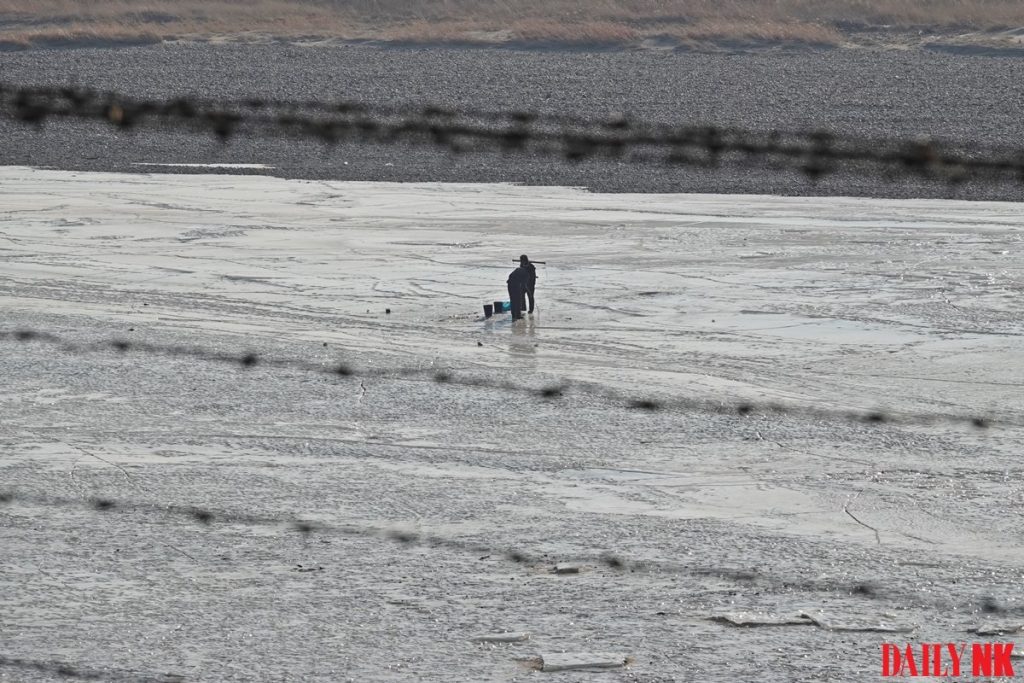 A North Korean resident in Onsong County, North Hamgyong Province draws water from the frozen river in March 2019