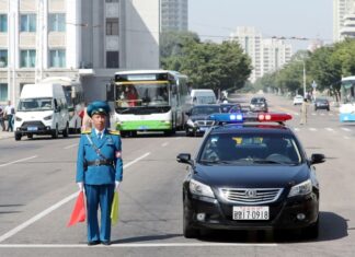 New drivers fuel rise in North Korea traffic accidents North Korean traffic police officer directing traffic on wide street in Pyongyang with police car, buses, and vehicles. driving