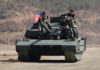 Kim Ju Ae drives a new-model North Korean tank during a combined arms tactical exercise at Pyongyang's 60th Training Base, March 19, 2026, as Kim Jong Un and military officers look on