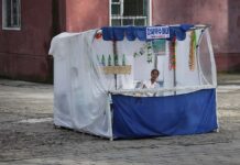 A vendor sits at a street stall selling Gangseo mineral water in Pyongyang, North Korea