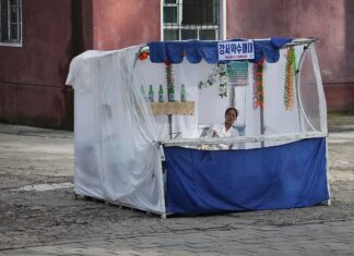 North Korean neighborhoods see rise of privately run makeshift stalls A vendor sits at a street stall selling Gangseo mineral water in Pyongyang, North Korea
