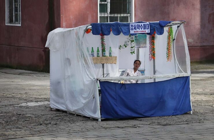 North Korean neighborhoods see rise of privately run makeshift stalls A vendor sits at a street stall selling Gangseo mineral water in Pyongyang, North Korea