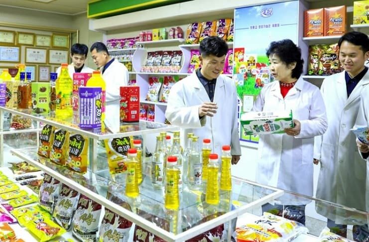 Workers in white lab coats inspect food products on display at the Amnok River General Food Factory in North Korea.