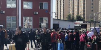 Chinese tourists with luggage gathered outside the Dandong customs checkpoint in Liaoning province, China