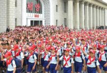 Korean Children's Union delegates in red caps and neckerchiefs wave outside Pyongyang Station after arriving for the organization's 80th anniversary celebrations.