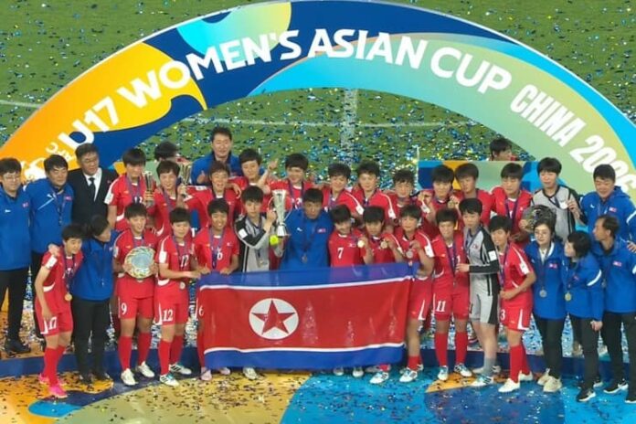North Korea's U-17 women's soccer team celebrates winning the 2026 Asian Cup with the trophy and national flag