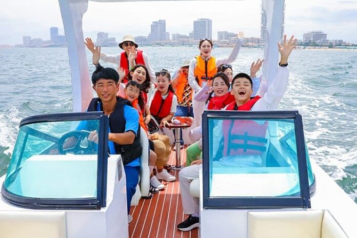 Visitors enjoy a speedboat ride at the Wonsan Kalma Coastal Tourist Zone, with resort hotels visible on the shoreline in the background.