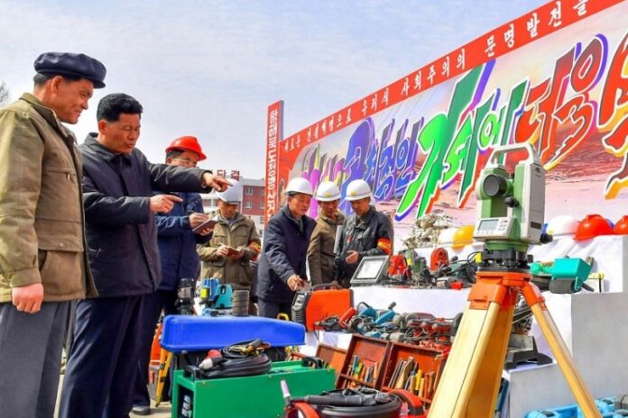 North Korean officials inspect construction equipment at a rural housing construction site
