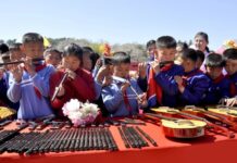 North Korean schoolchildren play piri flutes beside guitars laid out for a Kim Jong Un instrument donation