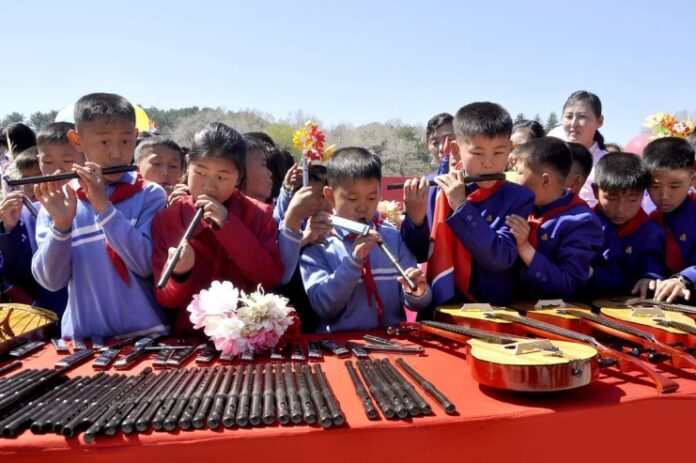 kim-jong-un-gift-instruments-flood-schools North Korean schoolchildren play piri flutes beside guitars laid out for a Kim Jong Un instrument donation