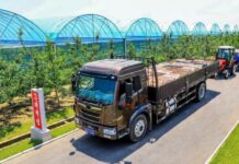 Truck hauling produce past greenhouse tunnels at Yonpho Greenhouse Farm, July 2026