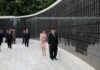 Kim Jong Un and Kim Ju Ae walk past a wall inscribed with names at the Taesong Mountain Revolutionary Martyrs' Cemetery in Pyongyang, flanked by North Korean officials, during an Aug. 14 visit marking the 81st anniversary of Korea's liberation.