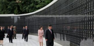 Kim Jong Un and Kim Ju Ae walk past a wall inscribed with names at the Taesong Mountain Revolutionary Martyrs' Cemetery in Pyongyang, flanked by North Korean officials, during an Aug. 14 visit marking the 81st anniversary of Korea's liberation.