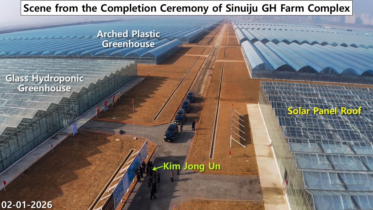 Rows of glass hydroponic and arched vinyl greenhouses along a central road at the Sinuiju greenhouse farm completion ceremony