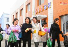 Women carrying shopping bags leave a local industrial factory store in Songchon county, North Korea