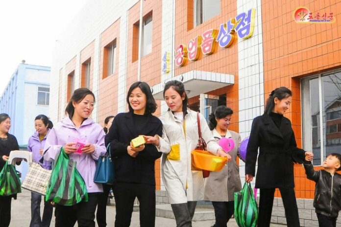 Women carrying shopping bags leave a local industrial factory store in Songchon county, North Korea