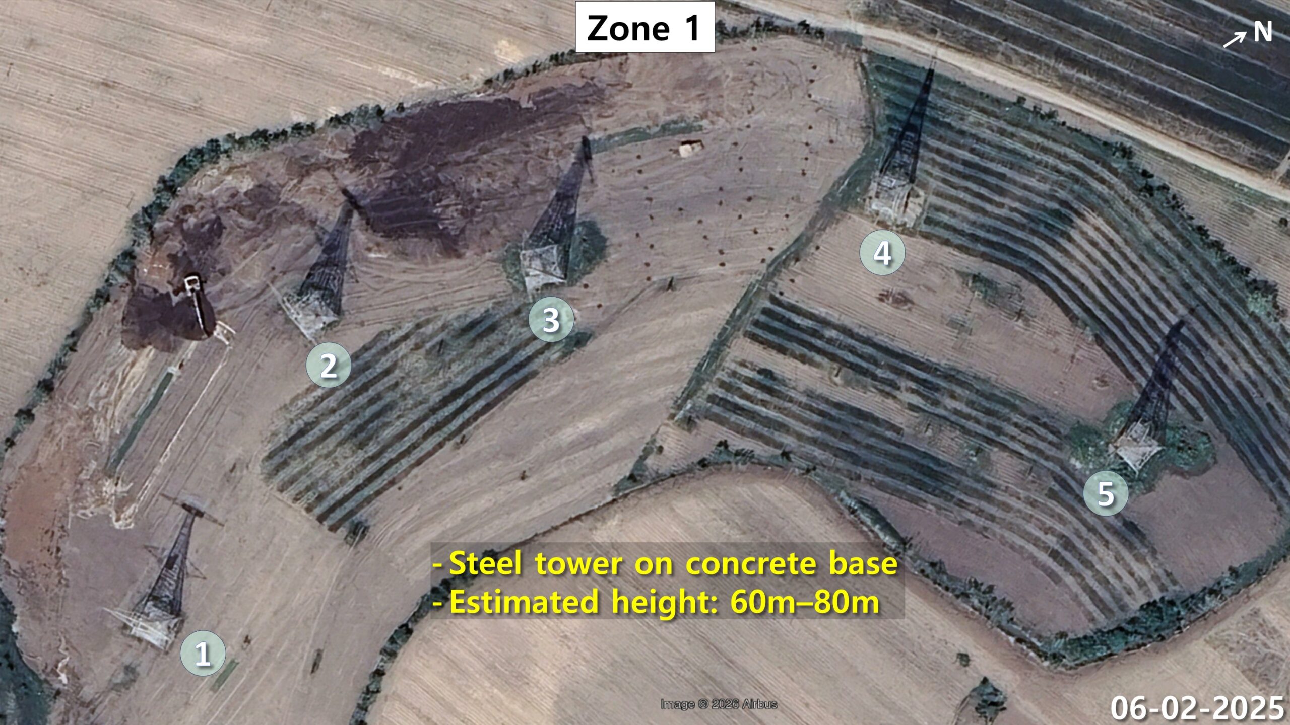 Five lattice transmitter towers on square concrete foundations spaced evenly across open ground in zone 1