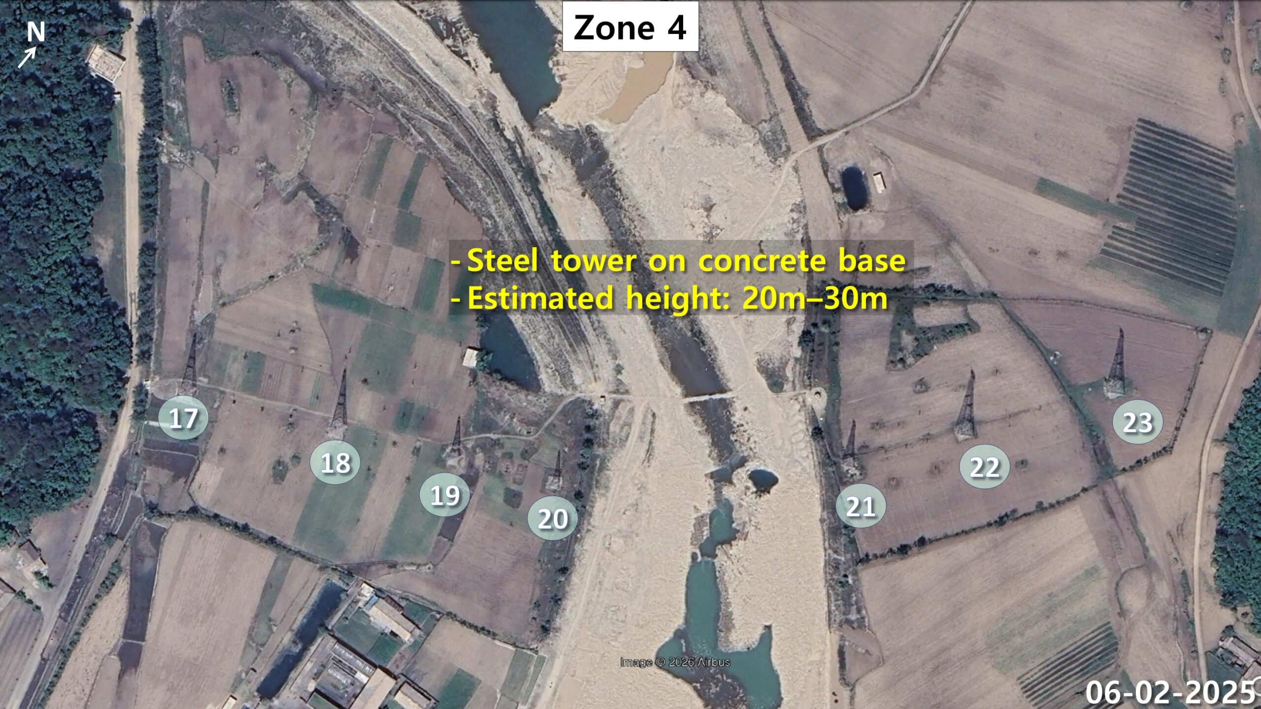 Seven transmitter towers on both banks of a river running through farmland and forest in zone 4